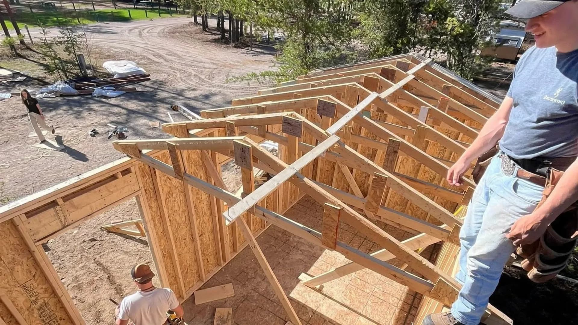 Charpentiers montant les fermes de toit d’un agrandissement en construction.