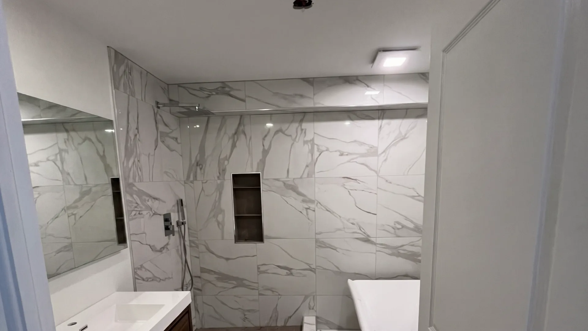 Salle de bain terminée : douche à l’italienne en céramique effet marbre, bain autoportant.